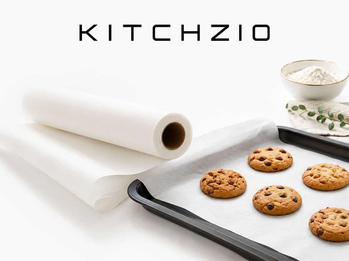 Kitchzio baking paper roll beside a baking tray of chocolate chip cookies